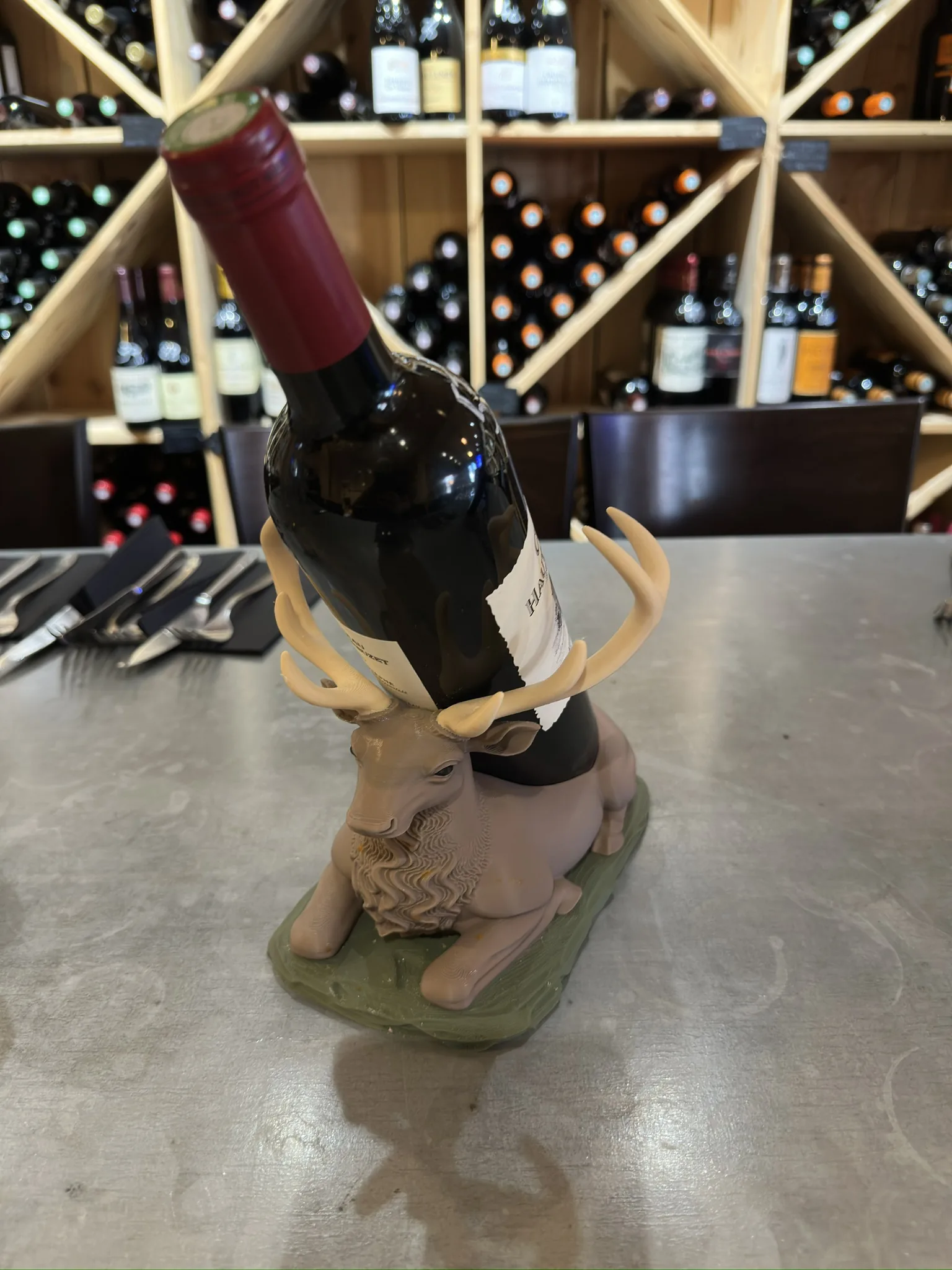 Support de bouteille en forme de tête de cerf rose tendre, imprimé en 3D, posé sur une table claire
